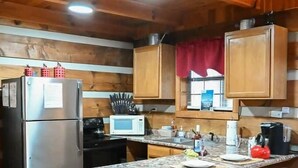 Une cuisine avec des meubles en bois, un réfrigérateur en acier inoxydable, un four à micro-ondes et un plan de travail en granit.
