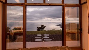 A room with a large sliding glass door leading to a view of a grassy area and a body of water. - Villa in Nature (Vila do Porto)