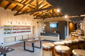 A modern interior with wooden beams, a reception desk labeled 'SANTORO', and shelves of jars. - Santoro Country House (Castiglione di Sicilia)