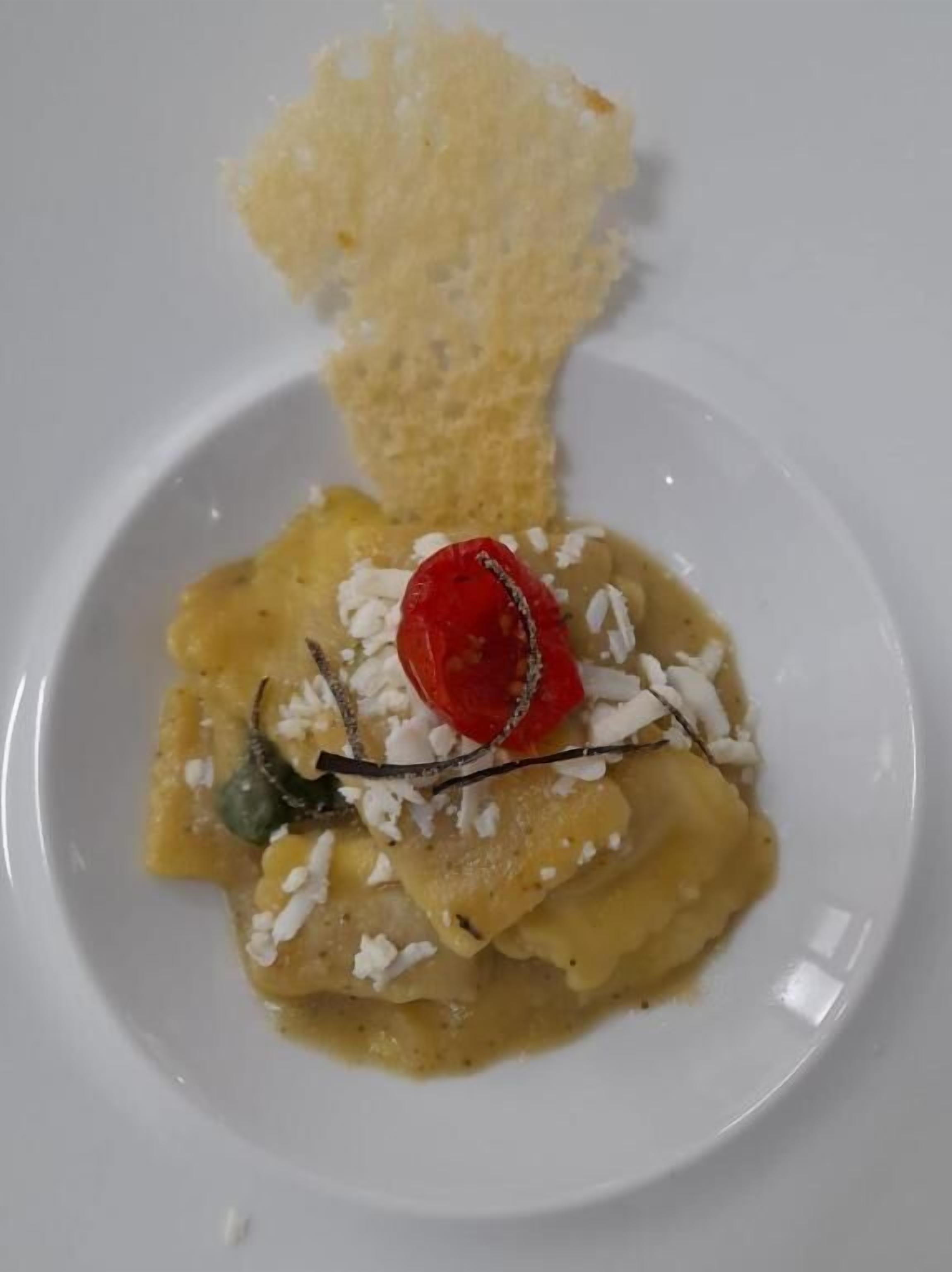 A plate with a food item, possibly a dessert, garnished with a cherry and a small green garnish.
