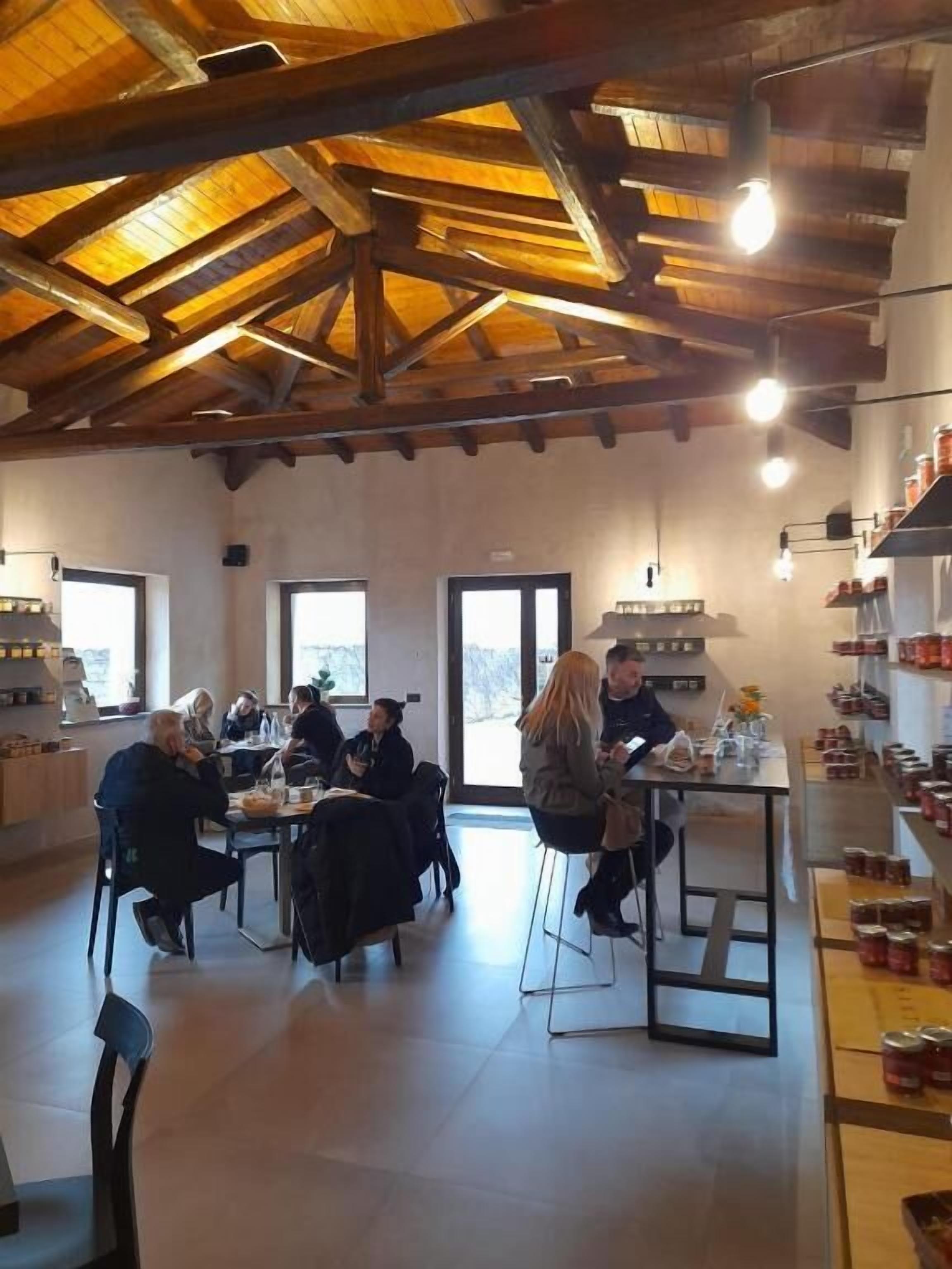 Un espace repas agrémenté de poutres en bois, de tables, de chaises et offrant une vue sur l’extérieur.