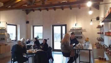 Un espace repas agrémenté de poutres en bois, de tables, de chaises et offrant une vue sur l’extérieur.