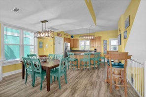 Una cocina luminosa con sillas color turquesa, una mesa de comedor de madera y una isla de cocina.