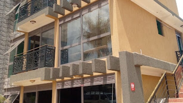 A multi-story building with a modern design, featuring large windows, a balcony, and a staircase. - Governors Hotel (Mukono)