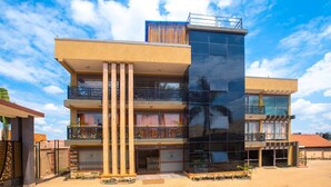 A modern multi-story building with balconies, a reception area, and a clear sky. - Governors Hotel (Mukono)