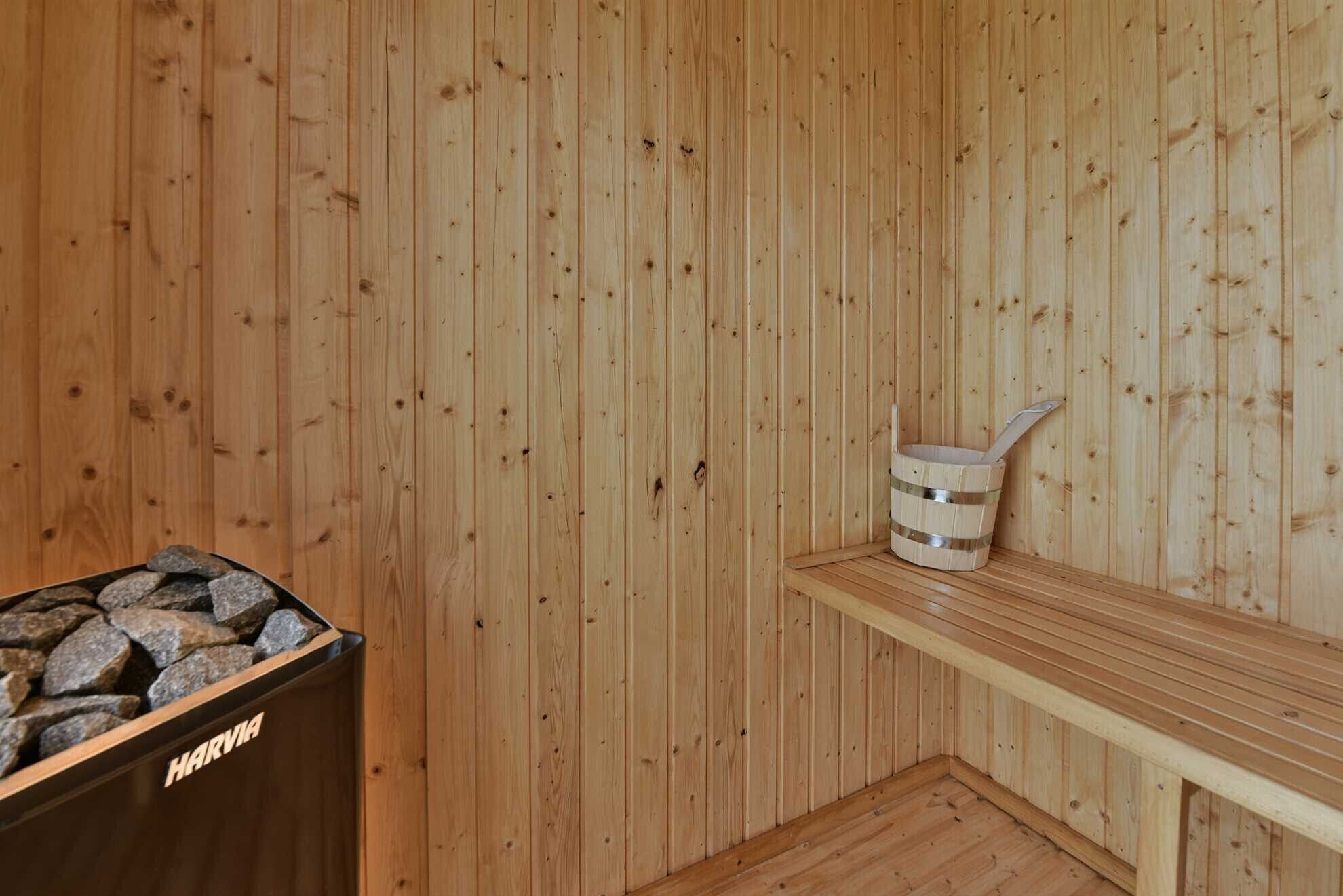 A wooden sauna room with a bench and a bucket.