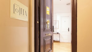 Una puerta de madera con un tirador de latón y una placa, una puerta blanca al fondo, y un suelo de madera.
