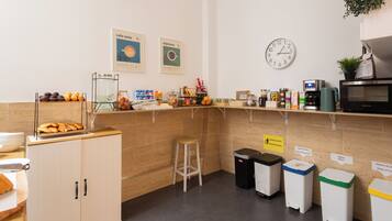 Un café équipé d’une machine à café, d’une horloge et de poubelles de tri.
