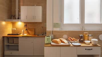 A modern kitchen with white cabinets, a wooden countertop, and a window with frosted glass.