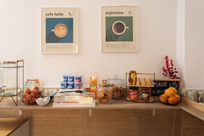 A cafe counter with coffee-making posters, a water dispenser, and various food items. - Casa Lolita Guesthouse (Barcelona)