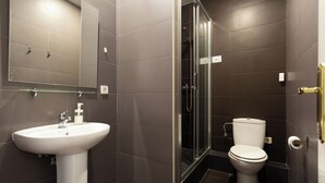 Een moderne badkamer met een wit wastafelmeubel, een glazen douchecabine en een toilet.