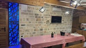 A rustic dining area with a stone wall, wooden beams, a table with a checkered tablecloth, and a bench. - La Vie Villa Jelena with rooftop pool, Zadar county (Zadar)