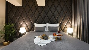 A modern hotel room with a tufted headboard, a neatly made bed with white linens, two bedside lamps, a small wooden side table with fruit and a bowl of berries, and a potted plant on the left side. - La Vie Villa Jelena with rooftop pool, Zadar county (Zadar)