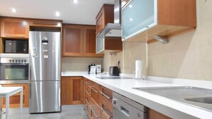 A modern kitchen with stainless steel appliances, wooden cabinets, and a white countertop. - Casa Jasmine, Modern Villa for 7 M-3 (Marbella)