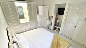 Un dormitorio con una cama grande, un armario blanco y un espejo.