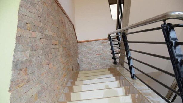 A staircase with a brick wall on one side and a metal railing on the other. - Day 2 Day Prime Hotel (Kampala)