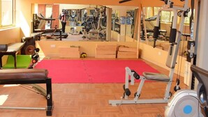 A gym with exercise equipment, a red mat, and a mirror reflecting the equipment. - Day 2 Day Prime Hotel (Kampala)
