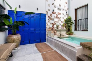 A pool area with a blue door, a small fountain, and potted plants.