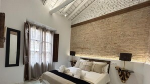 Een moderne slaapkamer met een groot bed, een houten bankje, een accentmuur van baksteen en een dakraam.