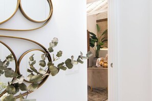 A doorway leading to a room with a plant, a lamp, and a small table with candles.
