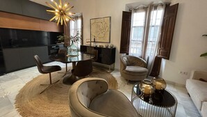 Een moderne woonkamer met een ronde eettafel, twee banken, een salontafel en een kroonluchter.