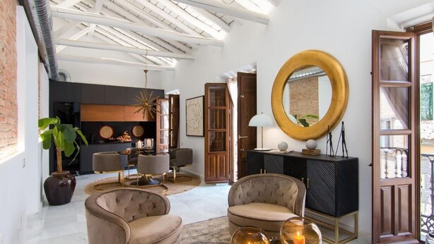 Een moderne woonkamer met een hoge plafond, een open haard, comfortabele zitplaatsen en een grote spiegel.
