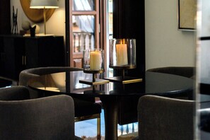 A dining table with two candles in glass holders, surrounded by chairs.