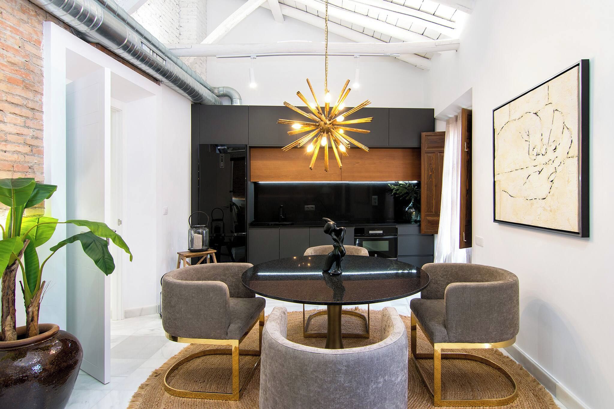 Un espace repas moderne avec une table ronde, quatre chaises et un lustre original.