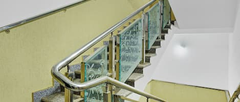 Un escalier doté de rampes en métal et de panneaux en verre ornés de motifs décoratifs.