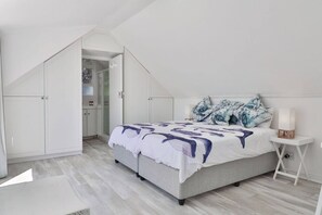 A bedroom with a bed, white wardrobe, and a small bedside table.