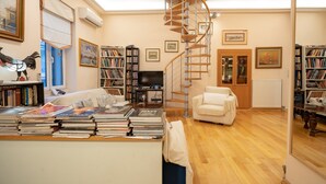 Un salón amplio con una escalera de caracol, un sofá, una mesa de centro con libros y una estantería.