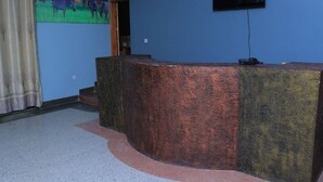 A reception area with a curved counter, a television mounted on the wall, and a door leading to another room. - Dream Wood Suites (Mbarara)