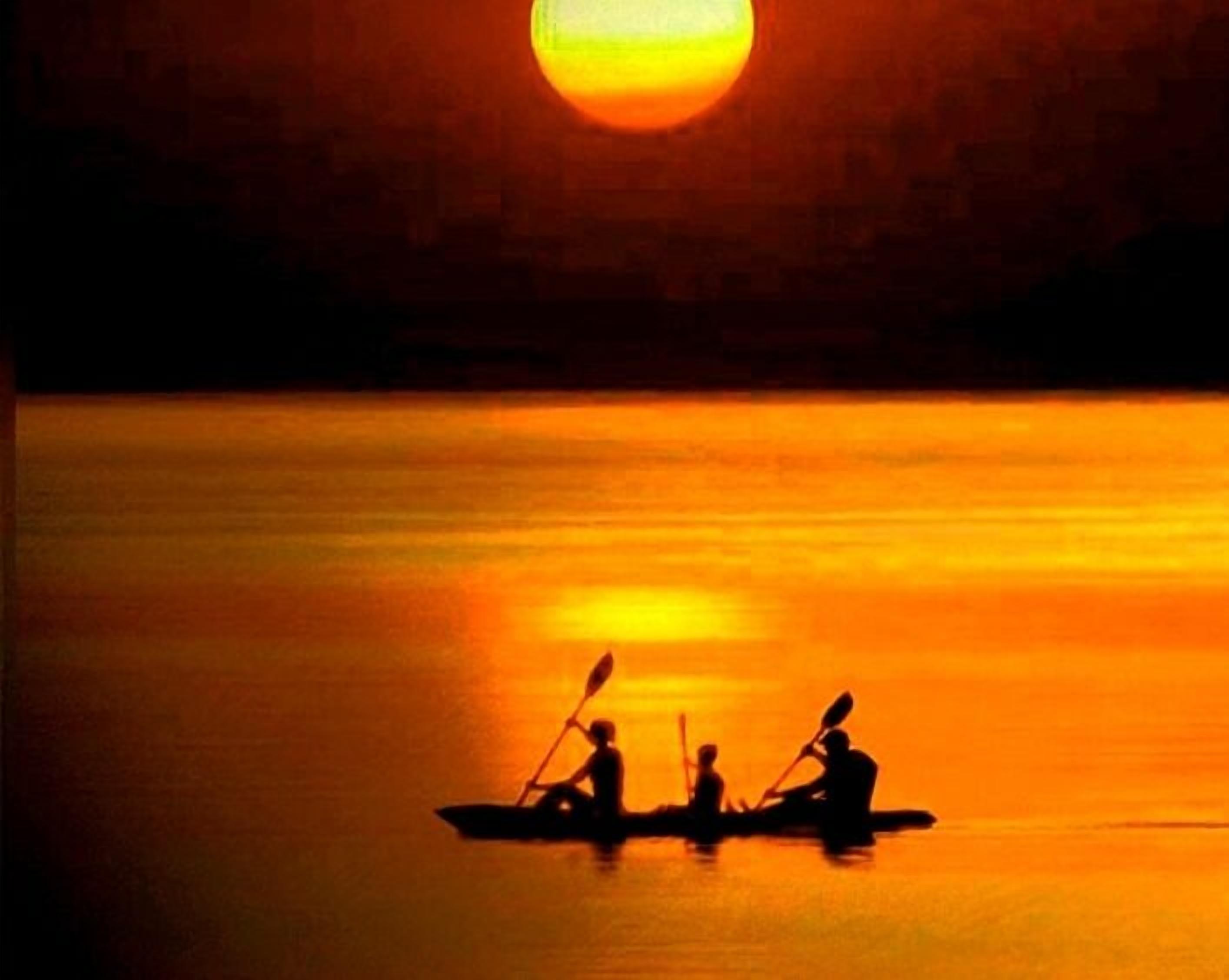 A sunset over a calm body of water with three people in a small boat.