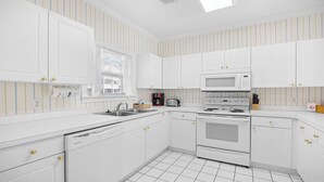 A kitchen with white cabinets, a microwave, a stove, and a dishwasher. - 813 Cypress Bend - Barefoot Resort Rentals (North Myrtle Beach)