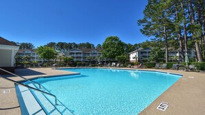 Une piscine avec des chaises longues et un bâtiment en arrière-plan.
