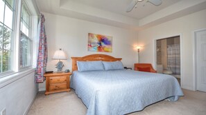 Une chambre à coucher avec un lit, une table de chevet, une lampe, un tableau et une porte de salle de bain.