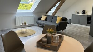 A modern loft apartment with a dining area, a sofa, a kitchen, and a skylight. - Schwan 6 - City center - 50m² - 2-room, KDB (Düren)