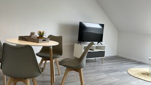 A modern dining area with a round table, chairs, and a television in the background. - Schwan 6 - City center - 50m² - 2-room, KDB (Düren)
