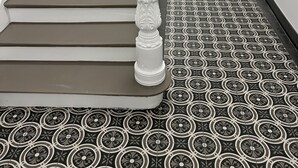 A staircase with a patterned floor and a white column. - Schwan 6 - City center - 50m² - 2-room, KDB (Düren)