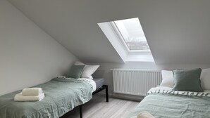 A bedroom with two beds, a skylight, and a radiator. - Schwan 6 - City center - 50m² - 2-room, KDB (Düren)