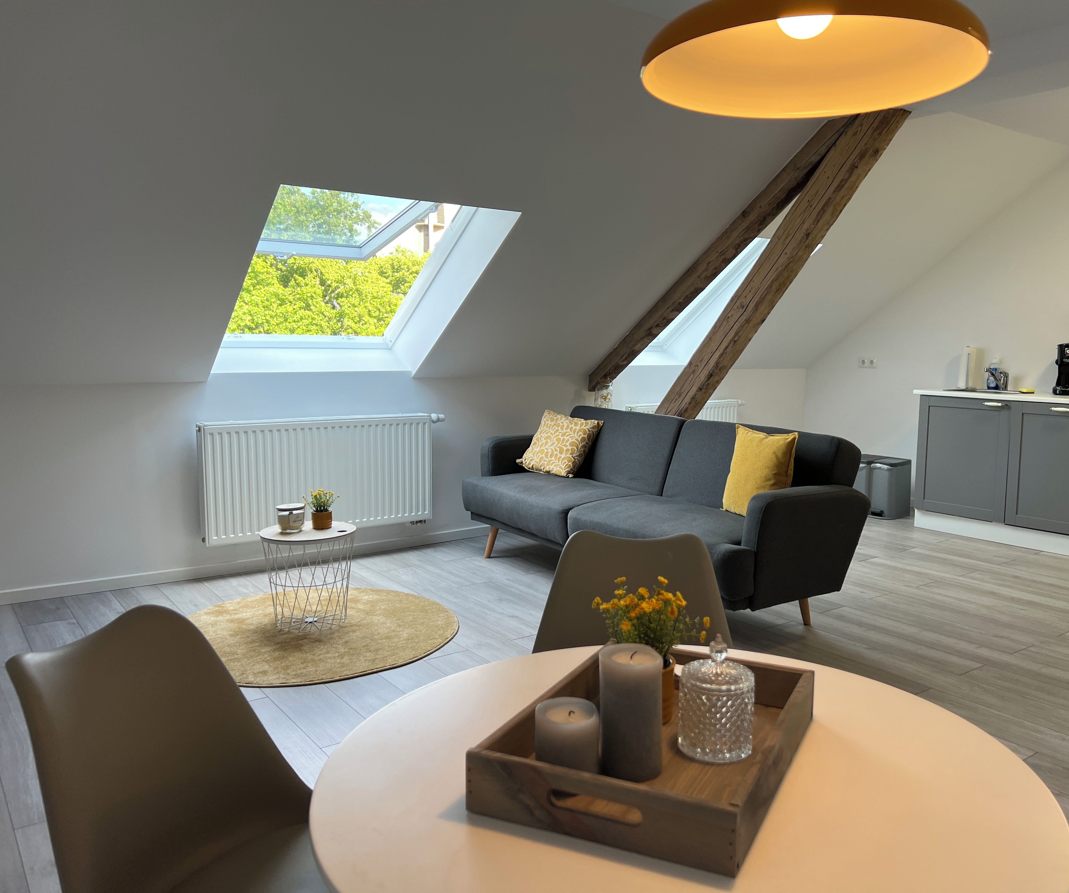 Een modern loft appartement met een eethoek, een bank, een keuken en een dakraam.
