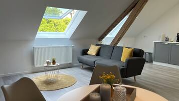 Een modern loft appartement met een eethoek, een bank, een keuken en een dakraam.