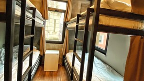A narrow, wooden-floored corridor with bunk beds on either side, a small white table, and a circular ceiling light. - Nomad Hostel Karakoy (Istanbul)