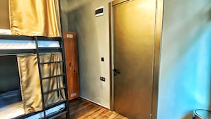 A room with a bunk bed, wooden flooring, a door, and an air conditioning unit. - Nomad Hostel Karakoy (Istanbul)