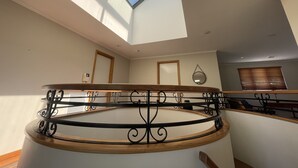 Ein geräumiges Zimmer mit Oberlicht, einer runden Wendeltreppe aus Holz und Metall sowie einer Holztür.