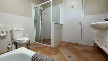 A bathroom with a toilet, shower, sink, and a bathtub.