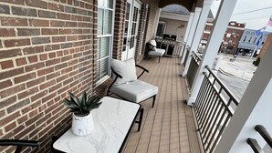 Un patio exterior cubierto con paredes de ladrillo, suelo de madera y mobiliario para exteriores.