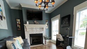 Una sala de estar con chimenea, un sofá modular, una mesa de centro y una lámpara moderna.