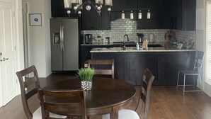 Una cocina moderna con armarios oscuros, una isla central y una lámpara de araña.