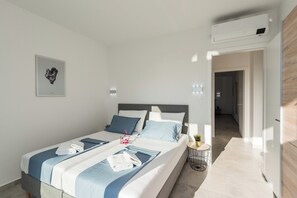 A modern hotel room with a large bed, a bedside table with a lamp, and a view of the hallway.